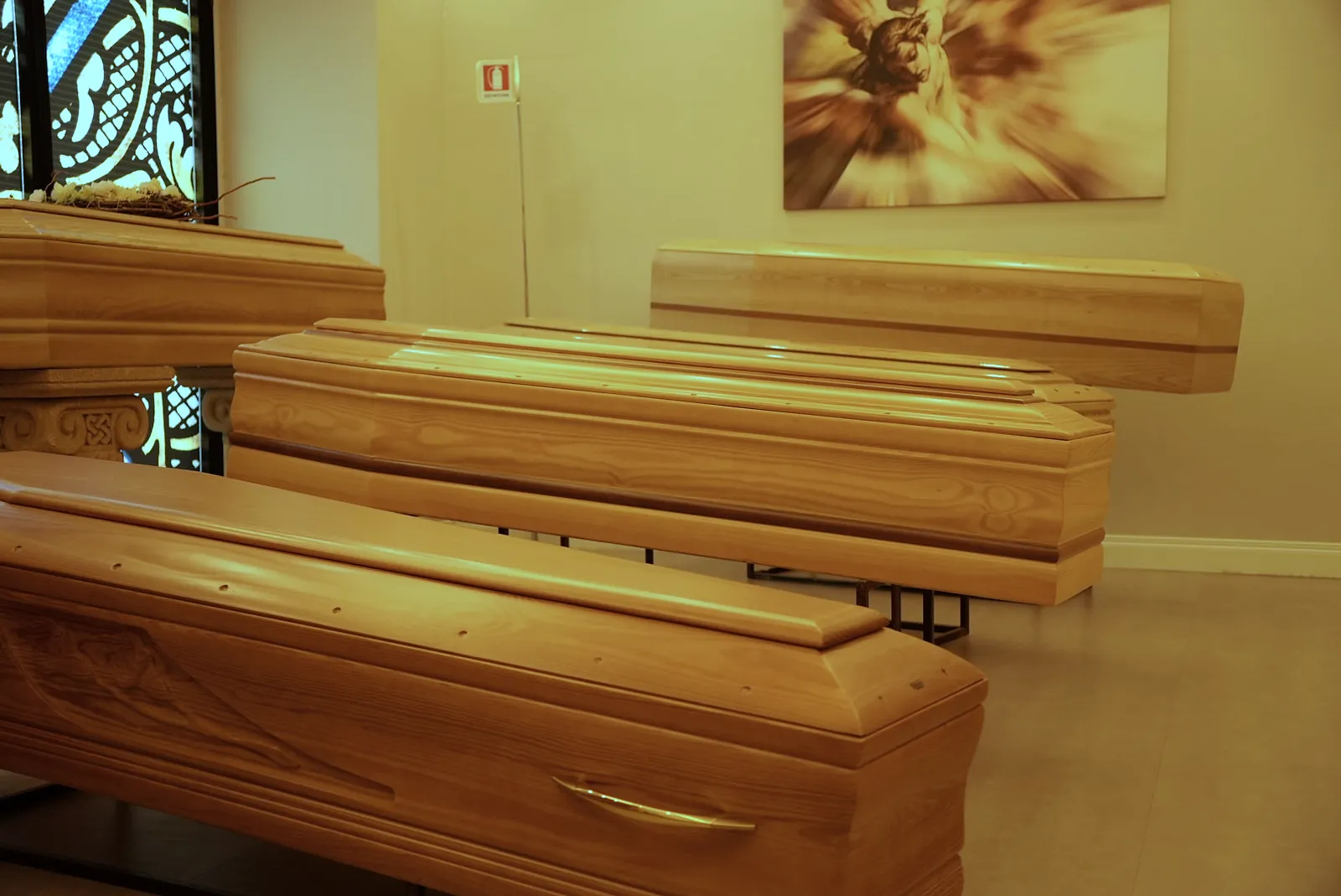 Cofani in legno massello nella sala esposizione, illuminati dalla vetrata artistica
